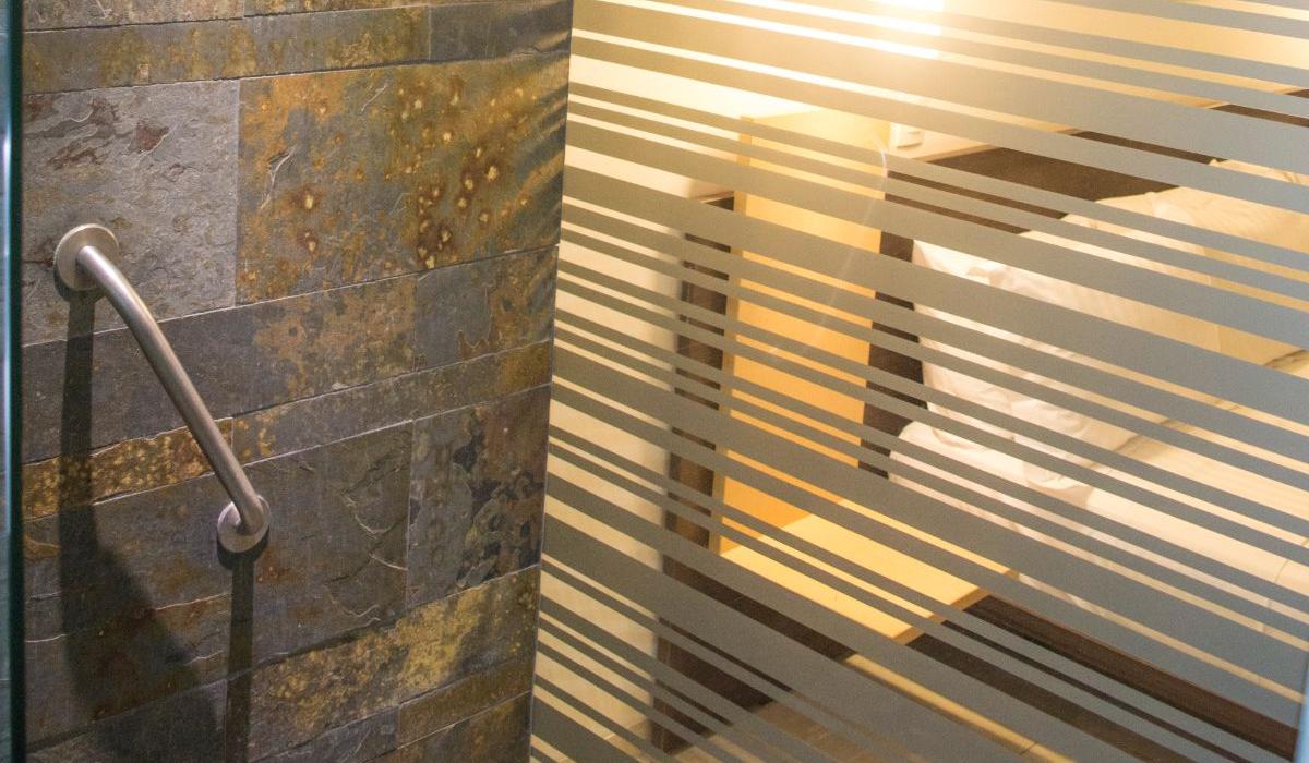 Baño contemporáneo con diseño elegante en Hotel Casablanca Cúcuta. Baño moderno con azulejos oscuros y división de vidrio esmerilado en Hotel Casablanca Cúcuta.
