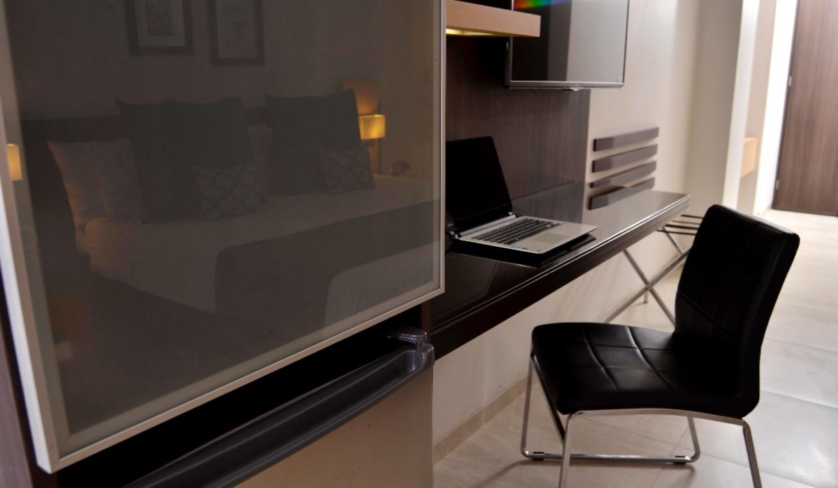 Escritorio funcional con laptop y TV en habitación del Hotel Casablanca Cúcuta. Escritorio con laptop, silla negra y TV en habitación moderna del Hotel Casablanca Cúcuta.