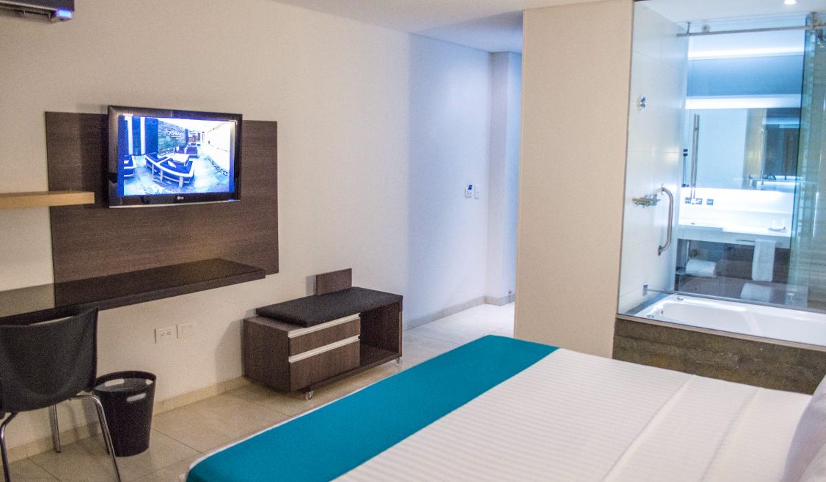 Habitación con cama king y baño con vidrio en Hotel Casablanca Cúcuta. Habitación con cama king, TV en pared y baño con vidrio en Hotel Casablanca Cúcuta.