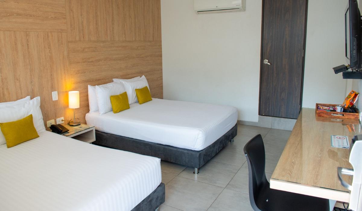 Habitación moderna con escritorio y aire acondicionado en Hotel Casablanca Cúcuta. Habitación doble con escritorio, silla negra, aire acondicionado y dos camas en Hotel Casablanca